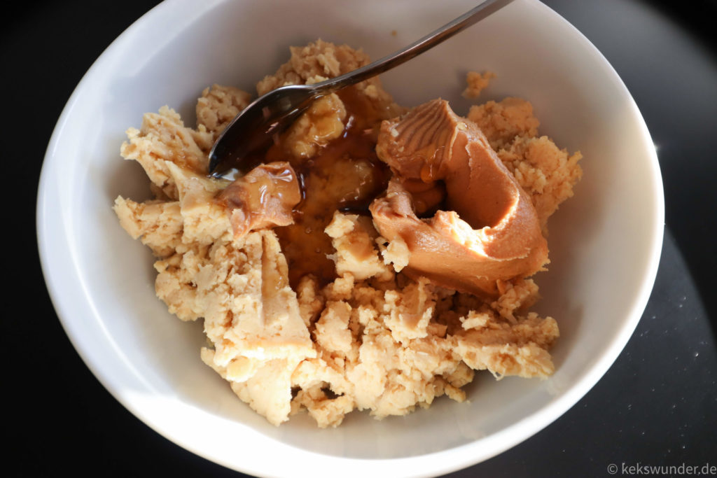 Kichererbsen mit Honig und Erdnussbutter in weißer Schale mit Löffel